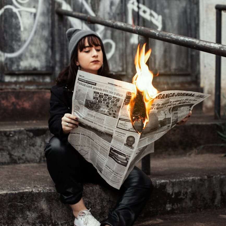 woman holding burning newspaper
